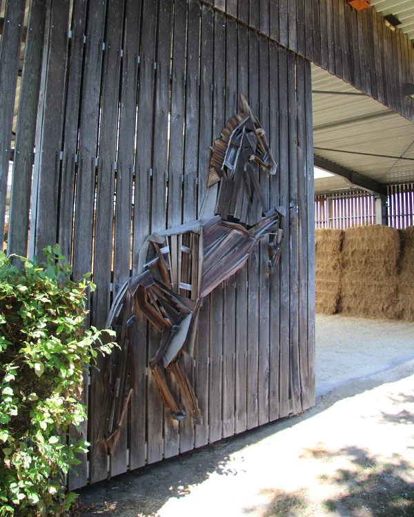 Een paard in hout aan de gevel van de binnenpiste van Stal Viktory.